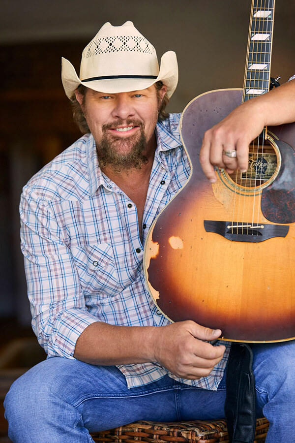 Toby Keith smiling while holding his guitar